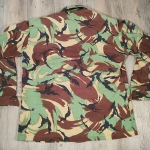 May include: A long-sleeved, button-up shirt with a camouflage pattern. The shirt is made from a cotton blend and has a relaxed fit.