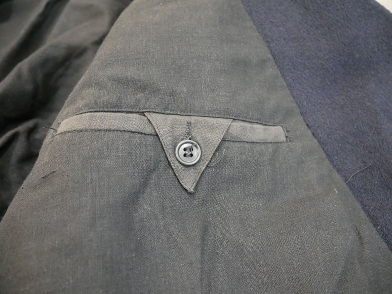 May include: Close-up of a black jacket with a single button on the inside pocket.