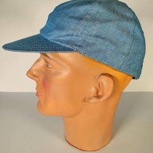 Op de afbeelding: Een blauwe denim baseballpet met een gebogen klep. De pet zit op een mannequinhoofd.