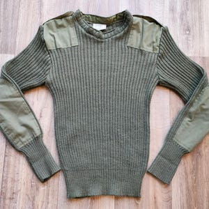 Puede incluir: Jersey de punto acanalado verde oliva con parches reforzados en hombros y codos. El jersey de manga larga tiene cuello redondo y un diseño de inspiración militar, perfecto para el uso diario.