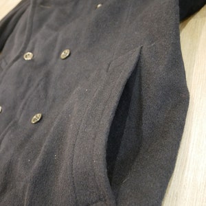 May include: A black wool peacoat with a double breasted closure and a large pocket on the right side.