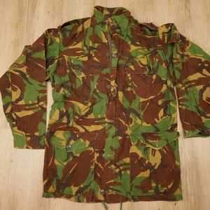 Peut inclure: Une veste de camouflage avec un devant boutonné et deux grandes poches. La veste est faite d'un tissu résistant et a un cordon de serrage à la taille.