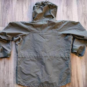 May include: A green hooded jacket with a drawstring hood and adjustable cuffs. The jacket has a zipper closure and a drawstring waist. The jacket is made of a lightweight material and is suitable for outdoor activities.