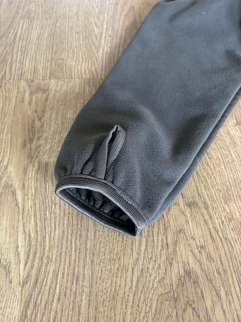 May include: Close-up of the dark green fleece cuff of a jacket with a sewn-in elastic band.