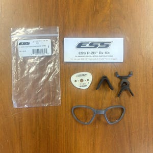 May include: ESS P-2B Rx Kit for use with ESS ICE Eyewear & Profile Series Goggles. The kit includes a pair of clear prescription lenses, a nose bridge, and two temple arms. The kit also includes a small white card with the text "P-28 N RX INSERT".