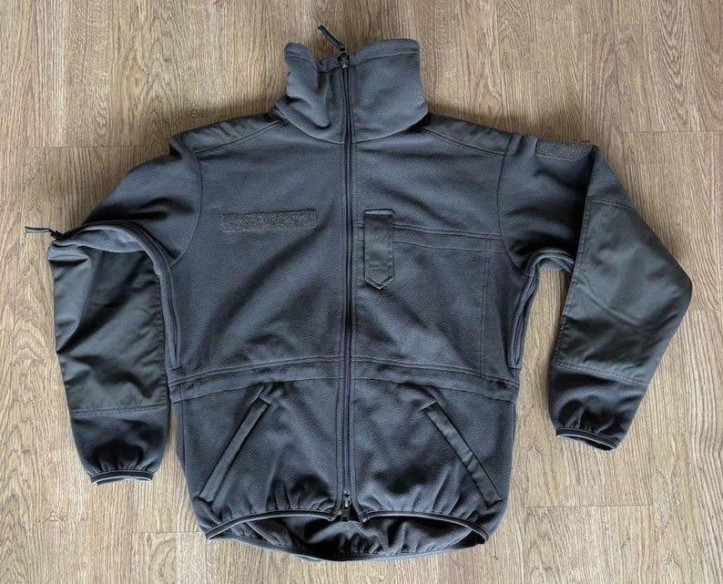 May include: A dark gray fleece jacket with a zipper closure and two pockets. The jacket has a high collar and a relaxed fit.