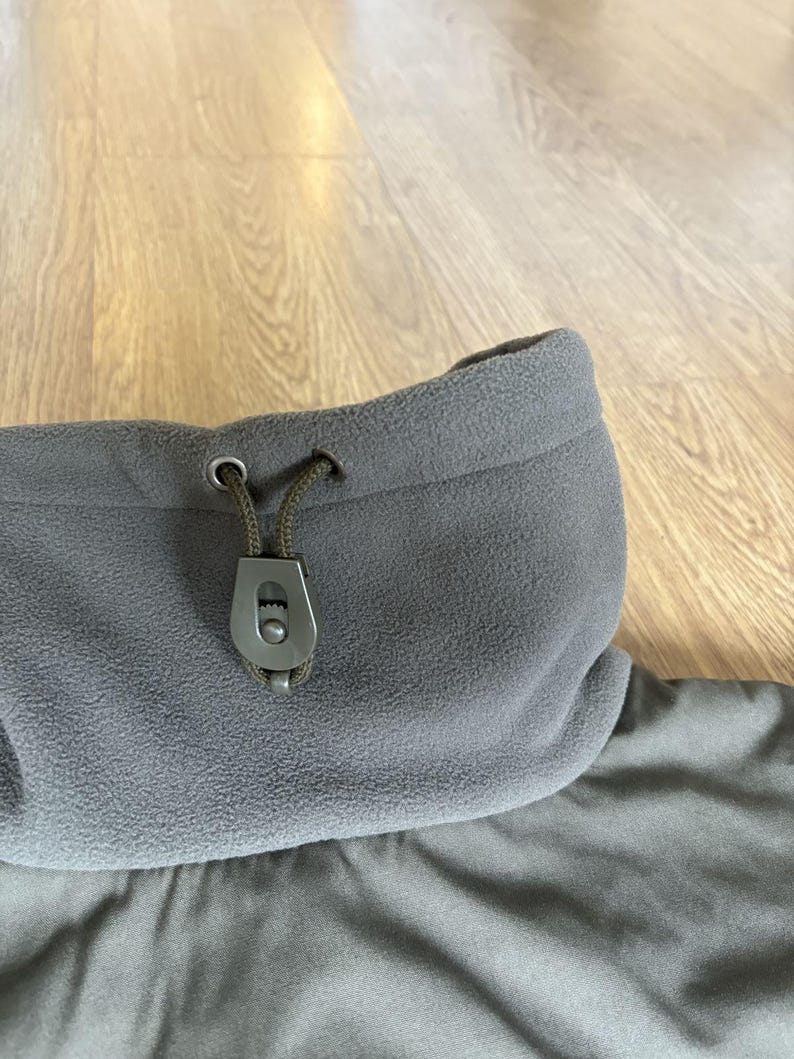 May include: A gray fleece jacket with a drawstring hood and a black toggle. The jacket has a zipper closure and a soft, comfortable feel.