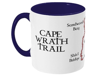 May include: White ceramic mug with a blue rim and handle. The mug features a black graphic of the Cape Wrath Trail with the text "Cape Wrath Trail" and the names of locations along the trail: "Sandwood Bay" and "Shiel Bridge".