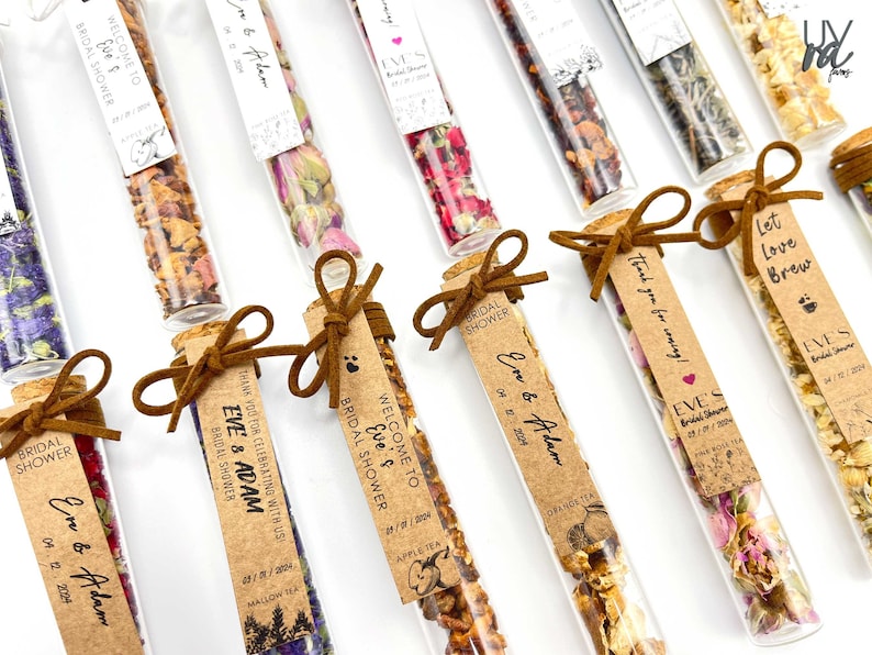 May include: Assortment of small glass test tubes filled with dried flowers and herbs, tied with brown ribbon and a personalized tag. The tags have the text "Welcome to Eve's Bridal Shower", "Thank you for coming!" and "Let Love Brew".