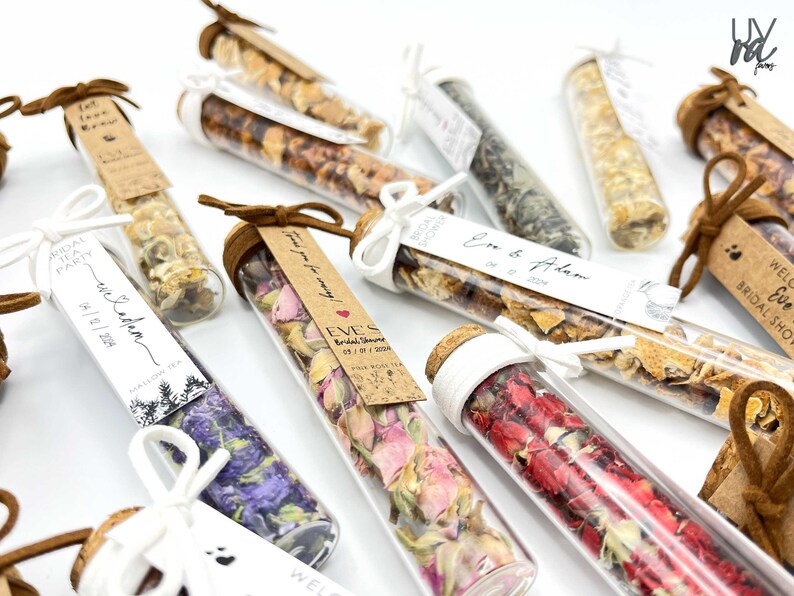 May include: Assortment of small glass tubes filled with dried flowers and herbs, tied with twine and a small tag. The tags have handwritten text, including "Bridal Shower", "Eve's", "05/1/2024", and "Thank you for coming!"