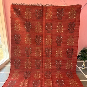 May include: Red, orange, and brown patterned rug with a geometric design. The rug has a fringe border.