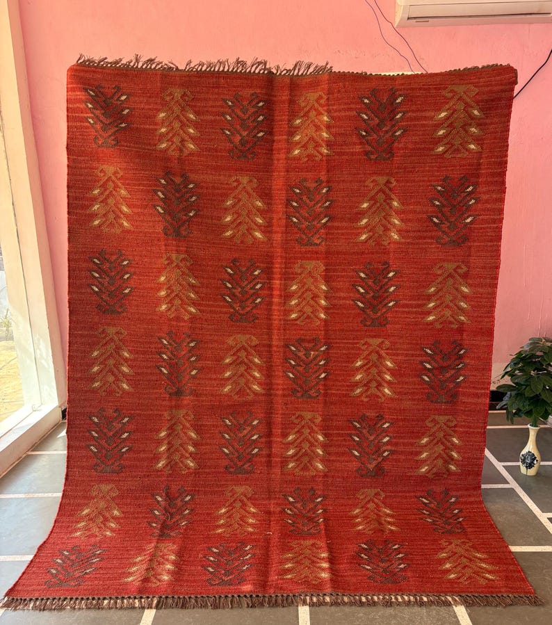 May include: Red, orange, and brown patterned rug with a geometric design. The rug has a fringe border.