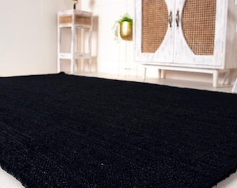May include: A black, woven rug with a textured surface. The rug is made of natural fibers and has a simple, modern design.