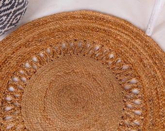 May include: A round, natural fiber rug with a woven design. The rug has a light brown color and a circular pattern in the center.