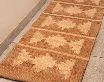 May include: A brown and beige woven rug with a geometric pattern. The rug is rectangular in shape and made from natural fibres.