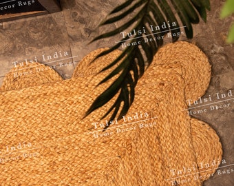 May include: A close-up of a natural fiber, beige, braided rug in the shape of a flower. The rug is made of thick, twisted rope and has a rustic, organic look. The text "Tulsi India Home Decor Rugs" is repeated throughout the image.