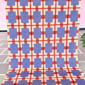 May include: A blue and red geometric patterned rug with a fringe border. The rug has a checkered pattern with squares of blue and red.