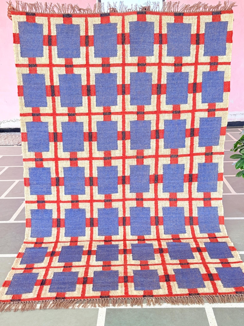 May include: A blue and red geometric patterned rug with a fringe border. The rug has a checkered pattern with squares of blue and red.