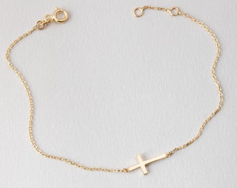 May include: A delicate gold chain bracelet with a simple cross pendant.