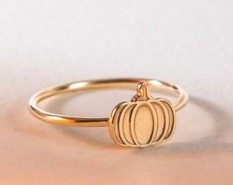 May include: A gold ring with a pumpkin design. The ring is simple and elegant, perfect for fall.