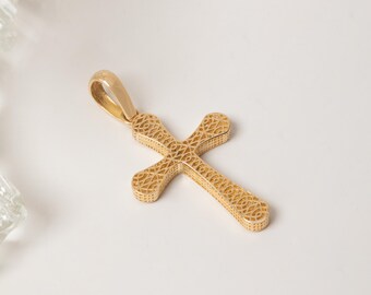 May include: A gold-toned cross pendant featuring an intricate, openwork filigree pattern throughout its surface. The cross has rounded ends and includes a smooth, solid gold-toned bail at the top for attachment to a chain or necklace.