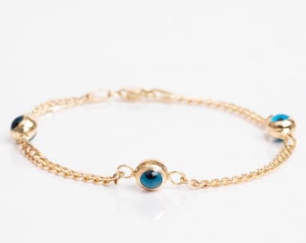 May include: A gold chain bracelet with three blue evil eye charms.