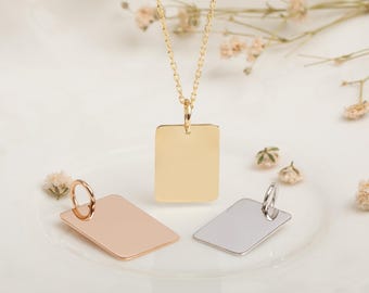 May include: A gold-colored rectangular pendant necklace with a delicate chain. Two additional rectangular pendants, one rose gold and one silver, are also displayed. The pendants are blank and have a polished finish. The background is a soft white.