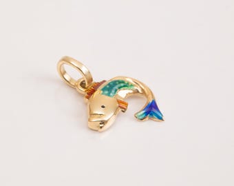 May include: A gold-colored fish charm with green, blue, and orange enamel details. The charm has a loop at the top for attaching to a necklace or bracelet.
