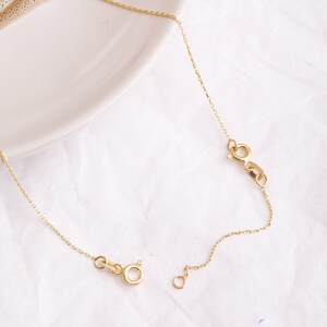 May include: A gold chain necklace with a lobster clasp and an extension chain. The chain is delicate and has a fine, linked design.
