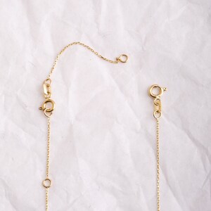 May include: A gold chain necklace with a lobster clasp and a small jump ring. The chain is delicate and has a fine link pattern.