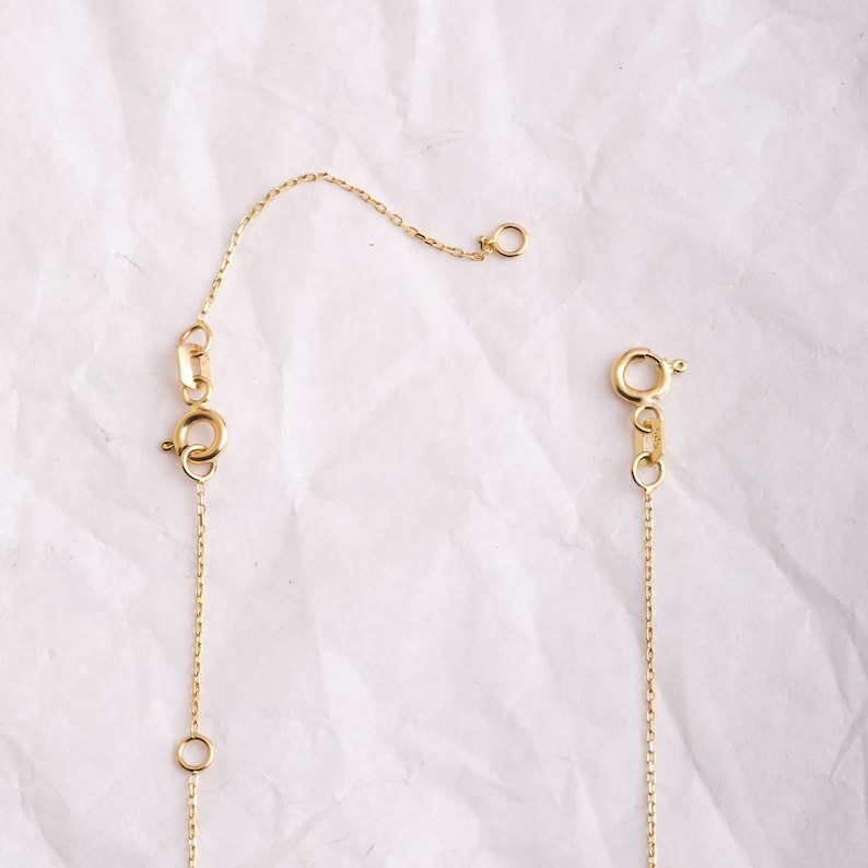 May include: A gold chain necklace with a lobster clasp and a small jump ring. The chain is delicate and has a fine link pattern.