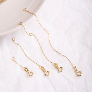 May include: Four gold extender chains of varying lengths, each with a lobster clasp closure.