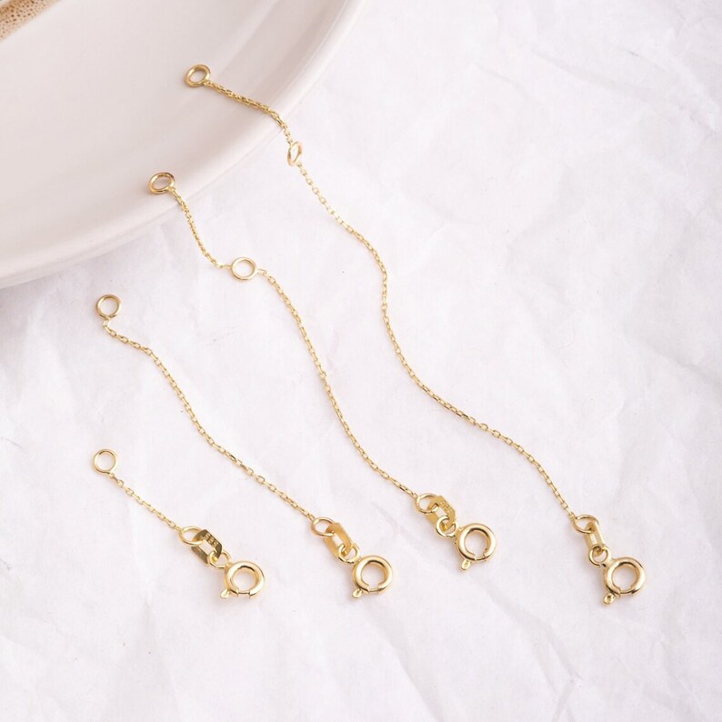 May include: Four gold extender chains of varying lengths, each with a lobster clasp closure.
