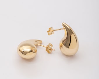 May include: A pair of gold teardrop-shaped earrings with a smooth, polished finish.