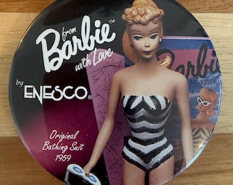 May include: A round pin featuring a Barbie doll in a black and white striped swimsuit. The pin has the text "from Barbie with Love" and "Original Bathing Suit 1959" with the ENECO logo. The background is black and purple.