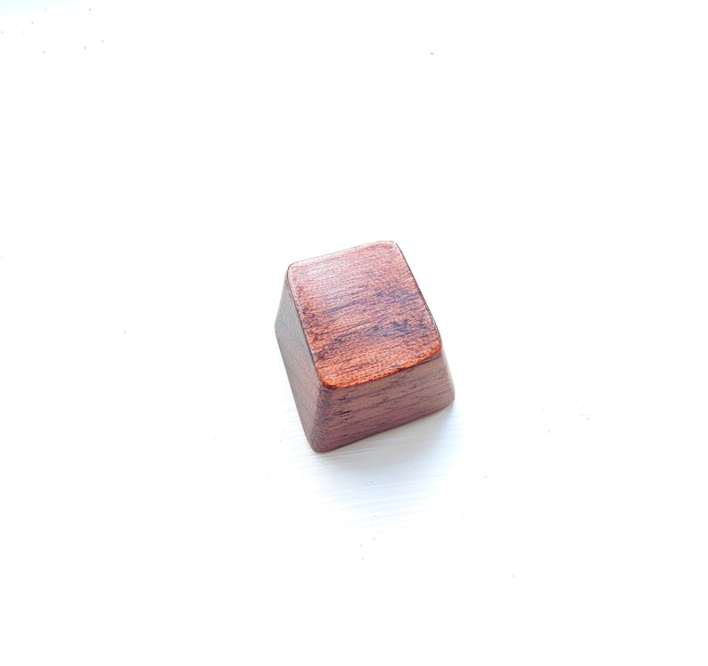 May include: A dark brown wooden keycap with a smooth, slightly textured surface.