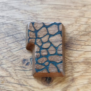 May include: A wooden keycap with a dark brown finish and a black geometric pattern.
