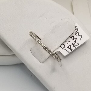 Puede incluir: Una fina banda de plata con peque&ntilde;os diamantes engastados en pav&eacute;. La banda est&aacute; sobre una tarjeta de presentaci&oacute;n blanca con una etiqueta escrita a mano que dice "D: .32 18K33".