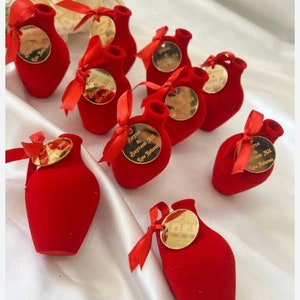 May include: Red velvet decorative vases with gold labels. The labels have the text "Beyza & Bayram Ali, 14 Haziran" on them.