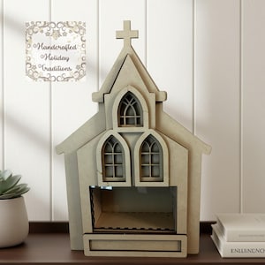 May include: A light brown wooden church-shaped decorative box with a cross on top and arched windows. The box has an open compartment at the bottom. The text "Handcrafted Holiday Traditions" is on a card in the background.