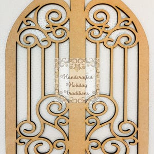 Puede incluir: Un marco de ventana arqueado de madera con intrincados adornos y barras verticales. El marco es de color marrón claro, con un diseño decorativo tallado en la madera. El texto "Handcrafted Holiday Traditions" es visible.