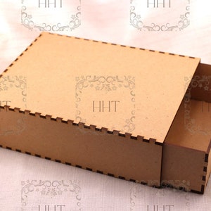 Puede incluir: Una caja de cartón marrón con un cajón que se desliza hacia afuera. La caja tiene un borde decorativo alrededor de los bordes.