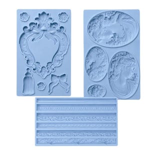 May include: Three light blue silicone molds for crafting. One mold features a heart-shaped frame with a bow, roses, and a bottle. Another has cameo portraits and floral designs. The third mold has decorative borders.