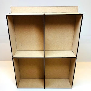 Puede incluir: Estantería de exhibición de madera marrón claro con cuatro compartimentos. La estantería tiene forma rectangular con lados inclinados y una pequeña balda superior. Los divisores verticales crean cuatro áreas de exhibición separadas.
