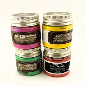 Könnte beinhalten: Vier Gläser Art Alchemy Opal Magic Acrylfarbe in den Farben Pink-Blau, Gelb, Teal-Pink und Korallen-Türkis. Jedes Glas hat einen silbernen Deckel und ein Etikett mit dem Markennamen und der Art der Farbe. Jedes Glas enthält 50 ml Farbe.