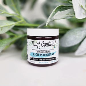 Pu&ograve; includere: Un barattolo di vernice anticata "Paint Couture" Rich Mahogany. L'etichetta indica che si tratta di una vernice a doppio uso e di una macchia semi-gel, a base d'acqua, e contiene 118 ml. Il barattolo ha un coperchio bianco e un corpo marrone scuro.