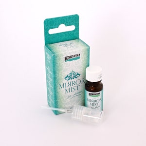 Może przedstawiać: Przezroczysta butelka Pentart Mirror Mist do tworzyw sztucznych, z zielono-białą etykietą. Butelka jest zapakowana w pudełko z zielono-białym wzorem i tekstem "Mirror Mist for plastic".