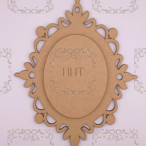 Op de afbeelding: Een houten frame met een decoratief, sierlijk ontwerp. Het frame is lichtbruin en heeft een uitsparing in het midden. Het frame is perfect om elke inrichting een vleugje elegantie te geven.