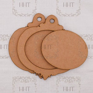 Op de afbeelding: Drie onafgewerkte houten ornamenten in de vorm van een cirkel met een decoratieve bovenkant. De ornamenten zijn op elkaar gestapeld.