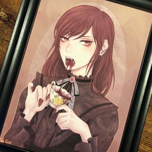 以下が含まれることがあります： 吸血鬼をテーマにしたイラストの額装アート。画像には、黒髪と赤い目の人物が、暗い液体が入ったティーカップを持っています。その人物は黒いドレスを着ており、口から血が滴っています。アートワークは黒いフレームに入っています。